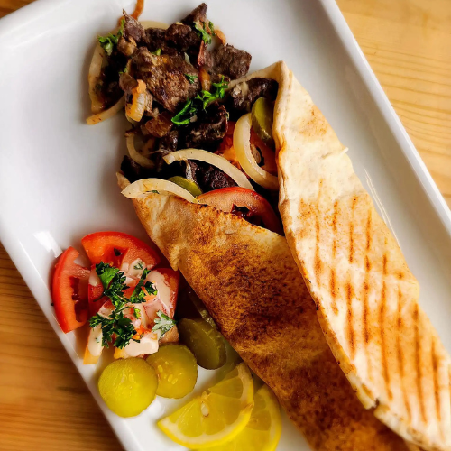 Beef Shawarma Sandwich - Marinated beef with hummus, tomatoes, and onions